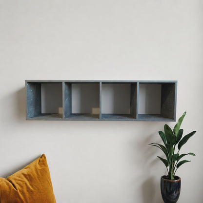 Rectangular grey shelf against a white wall with a plant and yellow cushion in the foreground.